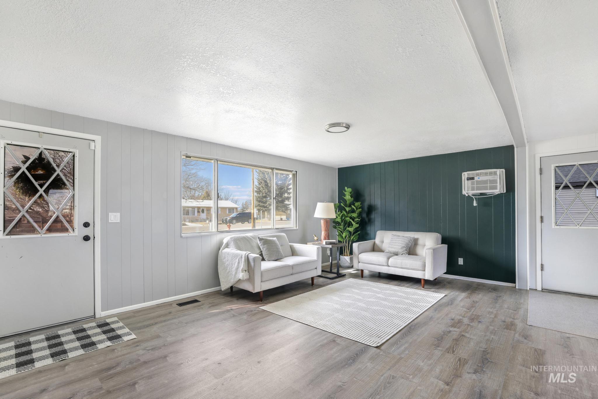 1840 V Street Heyburn, ID 83336 - Photo 4 of 45 Living area featuring a textured ceiling, wooden walls, and wood finished floors