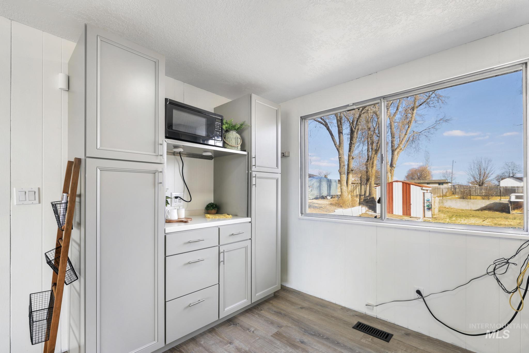 1840 V Street Heyburn, ID 83336 - Photo 7 of 45 Kitchen featuring black microwave, light wood-style flooring, light countertops, a textured ceiling, and gray cabinets