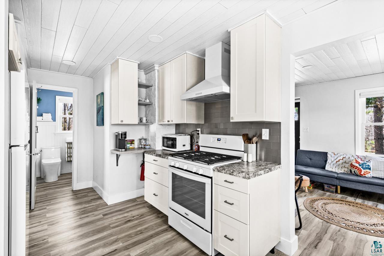 3645 Haines Road Hermantown, MN 55811 - Photo 26 of 35 Well-appointed kitchen featuring white cabinetry, modern appliances, wood-finish flooring, and a subway tile backsplash