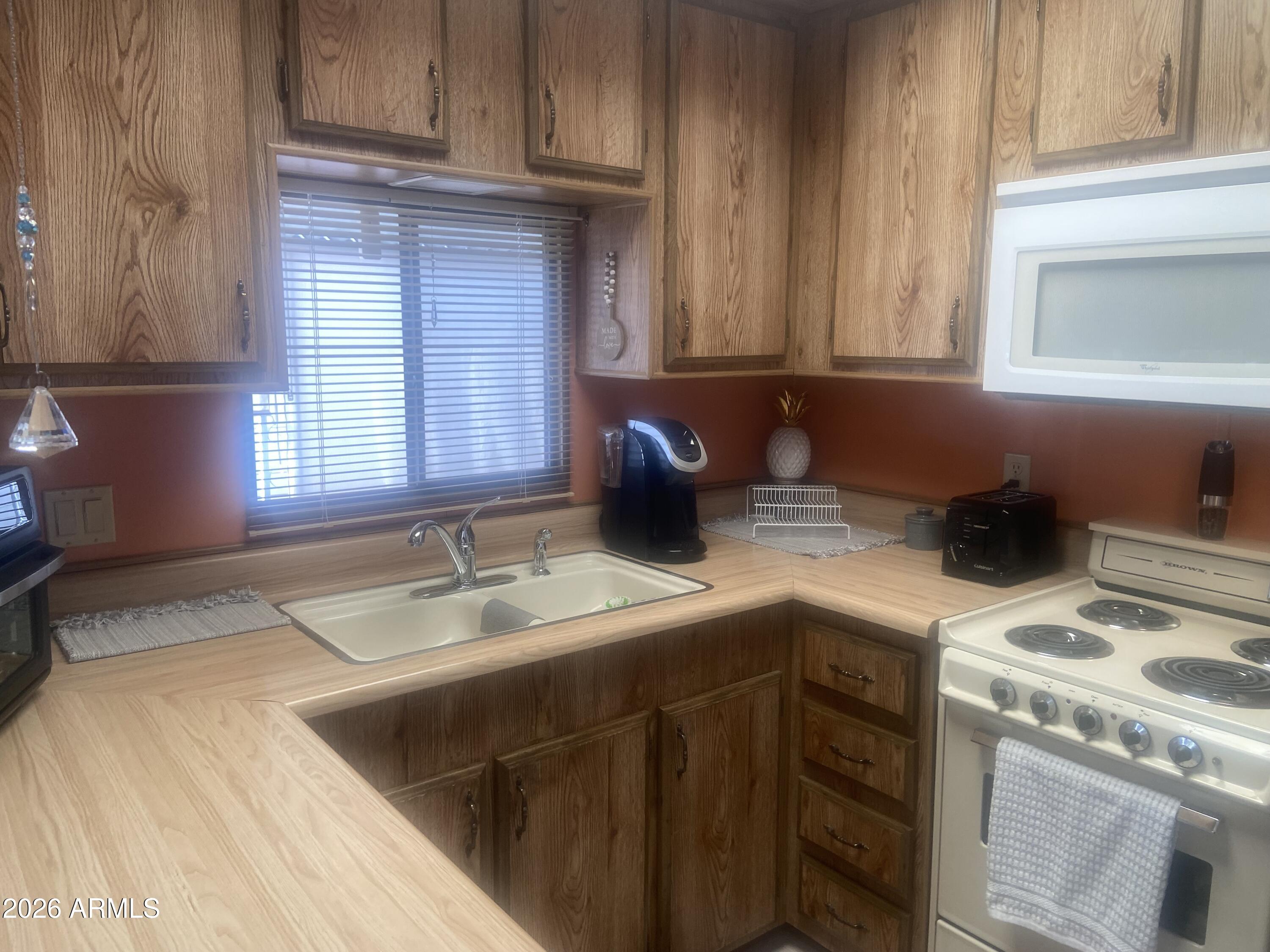 1340 West Inuit Avenue Apache Junction, AZ 85119 - Photo 8 of 30 a kitchen with stainless steel appliances granite countertop a sink stove and cabinets