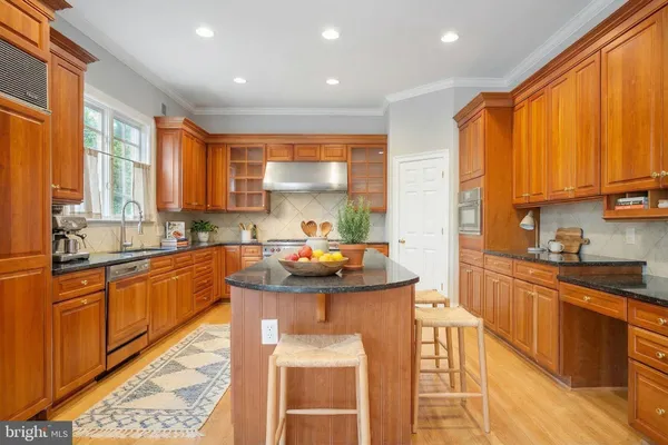 a kitchen with stainless steel appliances granite countertop a refrigerator a sink dishwasher a stove and white countertops with wooden floor