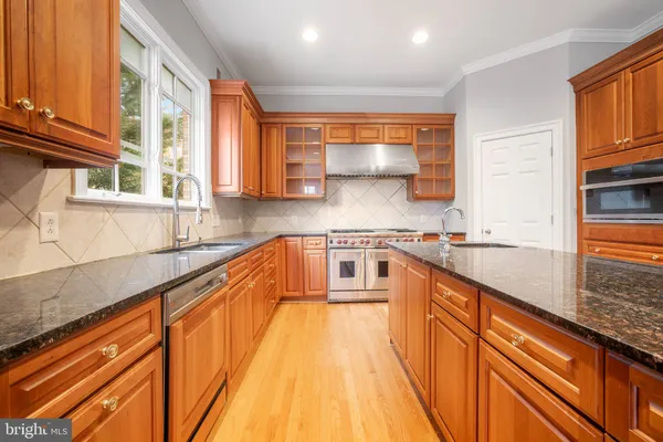 a kitchen with stainless steel appliances granite countertop a stove a sink and a refrigerator with wooden cabinets