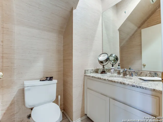 a bathroom with a granite countertop toilet sink and mirror