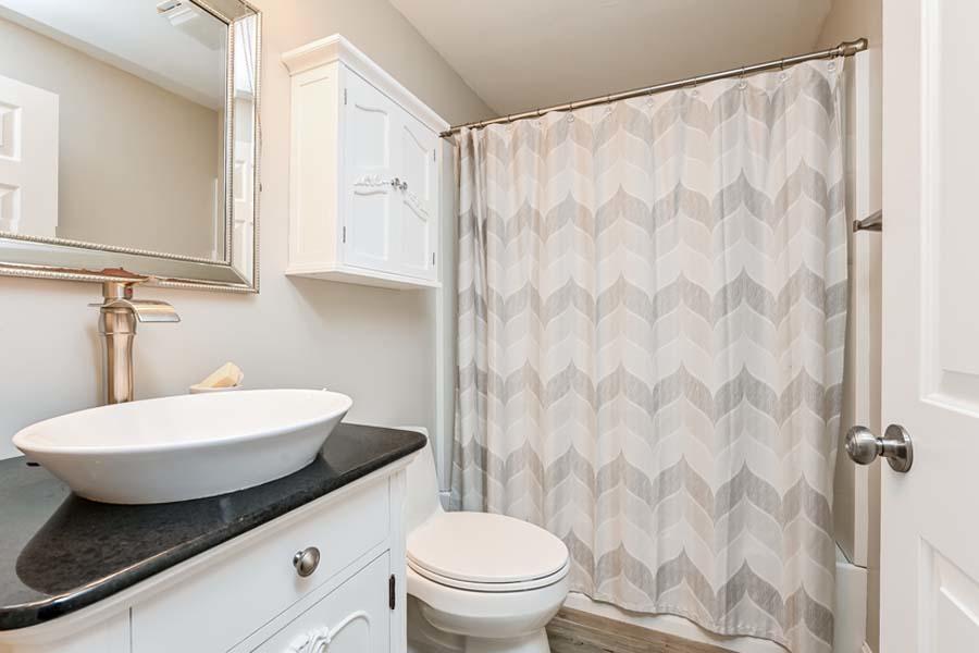 15 Riverview Avenue, Unit B Mashpee, MA 02649 - Photo 20 of 28 a bathroom with a sink a toilet a mirror and shower curtain