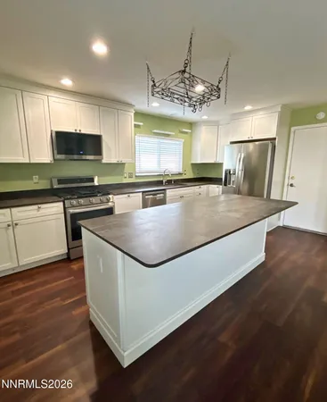 a kitchen with stainless steel appliances granite countertop a sink a stove top oven a counter space and cabinets