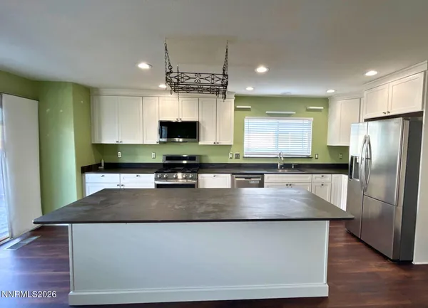 a kitchen with stainless steel appliances granite countertop a refrigerator a stove a sink a microwave and a refrigerator