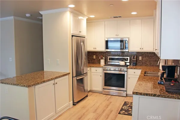 a kitchen with kitchen island granite countertop a stove a refrigerator and a sink