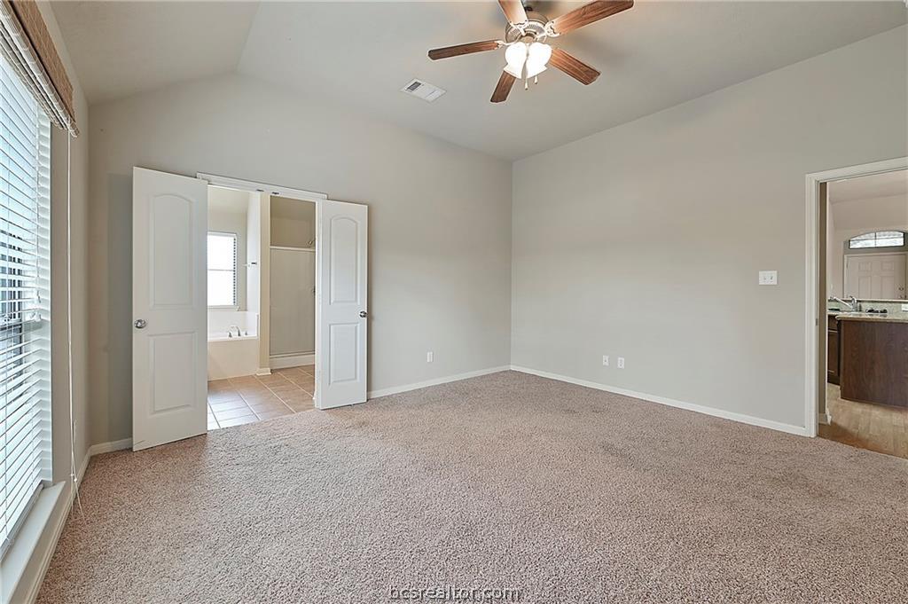 2004 Spring Leaf Court Bryan, TX 77807 - Photo 7 of 19 Spare room featuring visible vents, baseboards, ceiling fan, vaulted ceiling, and light colored carpet