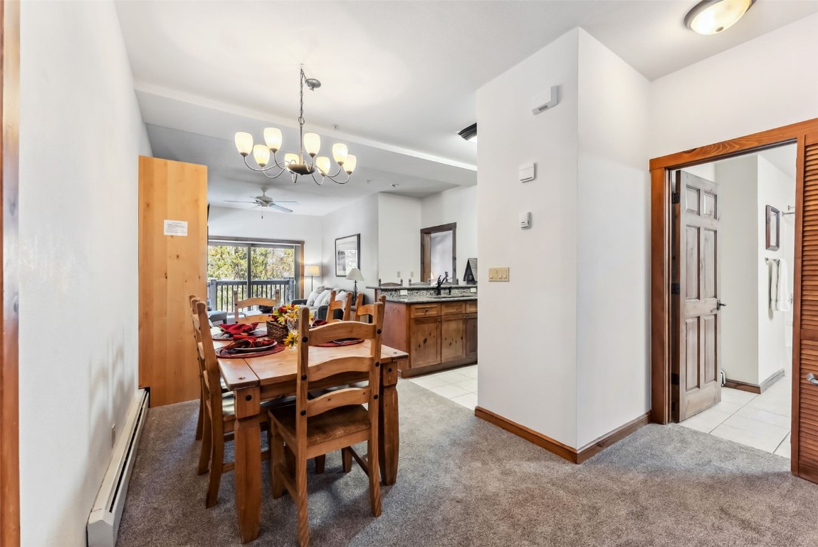 17 Lake Ridge Circle, Unit 1826 Keystone, CO 80435 - Photo 6 of 28 Dining room with baseboards, light tile patterned flooring, a baseboard radiator, light colored carpet, and ceiling fan with notable chandelier
