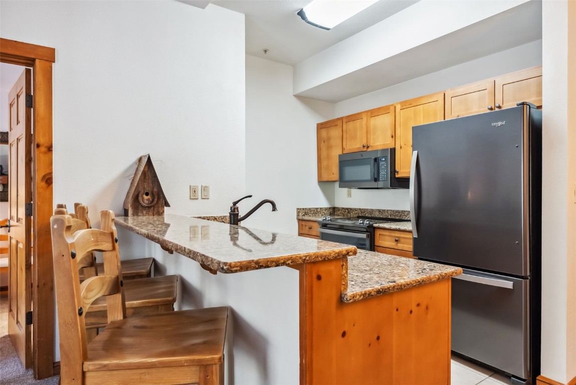 17 Lake Ridge Circle, Unit 1826 Keystone, CO 80435 - Photo 8 of 28 Kitchen with light brown cabinets, a sink, appliances with stainless steel finishes, a peninsula, and a breakfast bar area