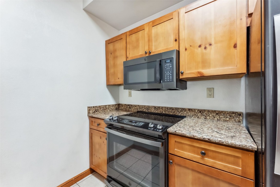 17 Lake Ridge Circle, Unit 1826 Keystone, CO 80435 - Photo 9 of 28 Kitchen with baseboards, black appliances, light tile patterned flooring, and light stone counters