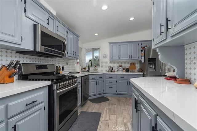 a kitchen with stainless steel appliances granite countertop a sink dishwasher stove top oven and cabinets with wooden floor