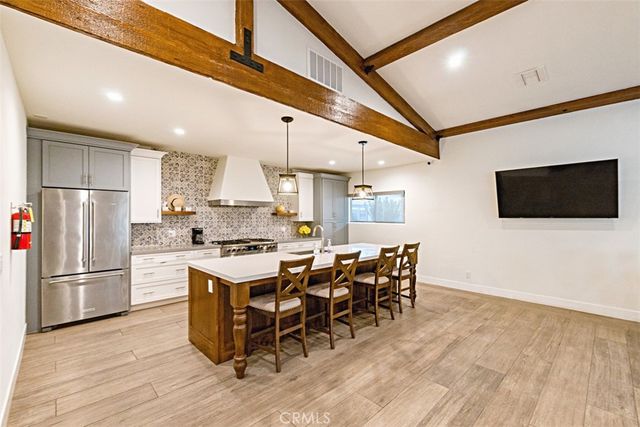 a kitchen with stainless steel appliances granite countertop a stove top oven a refrigerator a sink and a dining table with wooden floor