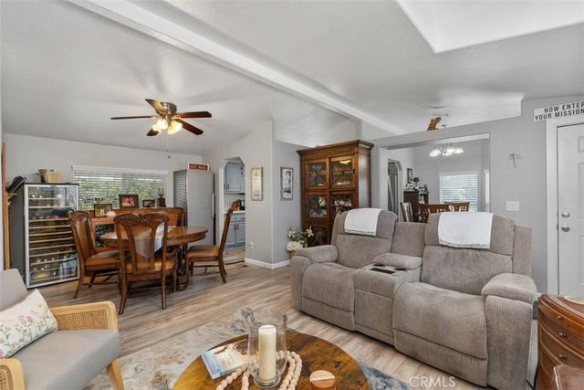 a living room with furniture kitchen view and a wooden floor