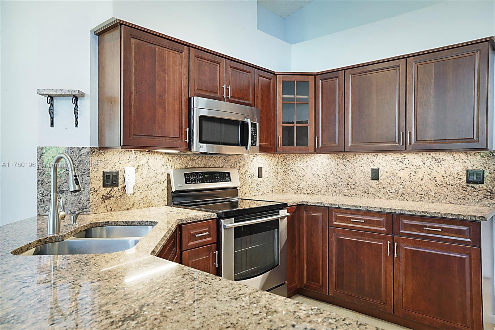 18295 Lake Bend Drive Jupiter, FL 33458 - Photo 16 of 64 a kitchen with granite countertop wooden cabinets a stove top oven a sink and dishwasher