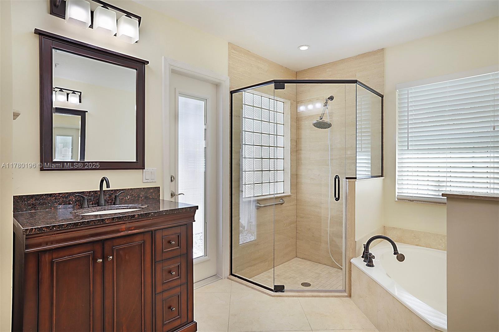 18295 Lake Bend Drive Jupiter, FL 33458 - Photo 27 of 64 a bathroom with a granite countertop sink a mirror and shower