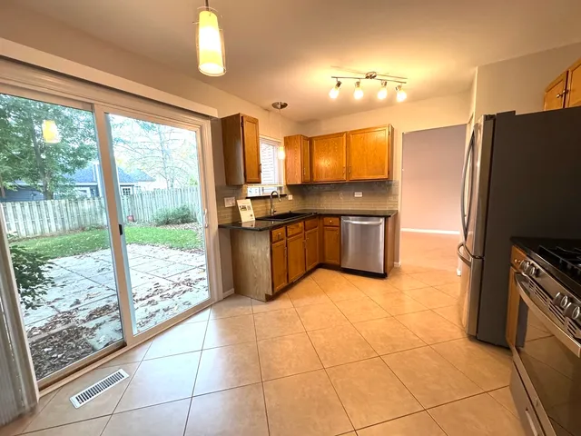 a kitchen with stainless steel appliances granite countertop a refrigerator a sink a stove top oven and a large window