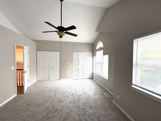 a view of a livingroom with a chandelier fan and windows