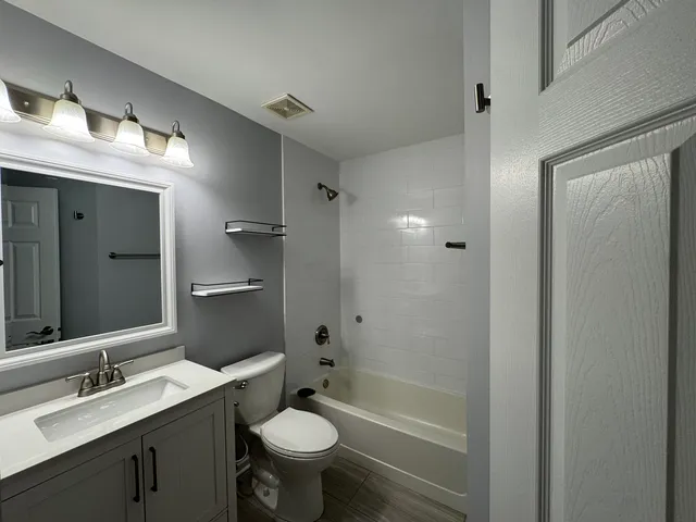 a bathroom with a bathtub shower sink vanity granite and toilet