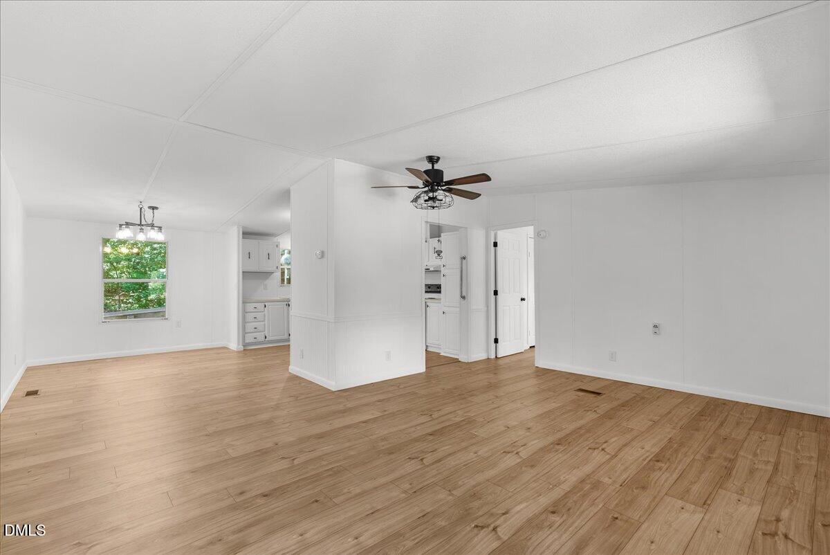 1111 Stoney Mountain Road Rougemont, NC 27572 - Photo 5 of 30 an empty room with wooden floor chandelier fan and windows