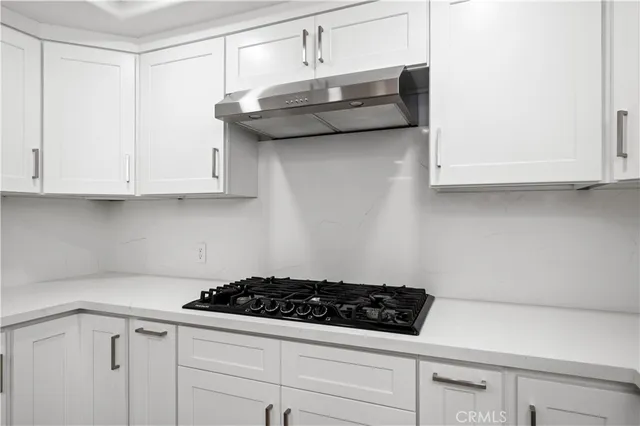 a kitchen with white cabinets and a stove