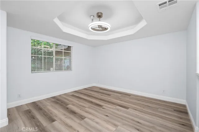 a view of empty room with wooden floor and fan