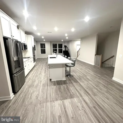 a living room with stainless steel appliances furniture wooden floor and a view of kitchen