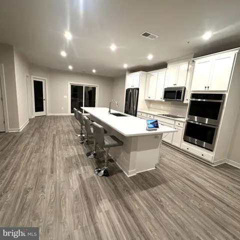 a large kitchen with stainless steel appliances a large counter top a stove and a wooden floors