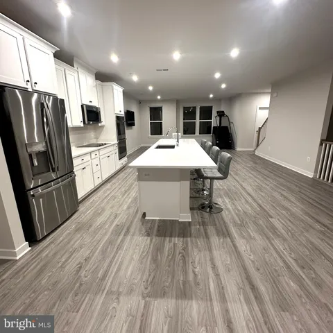 a view of kitchen with sink microwave refrigerator and wooden floor
