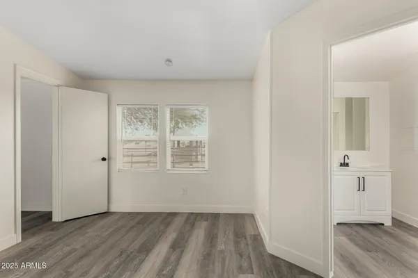 a view of an empty room with wooden floor and closet