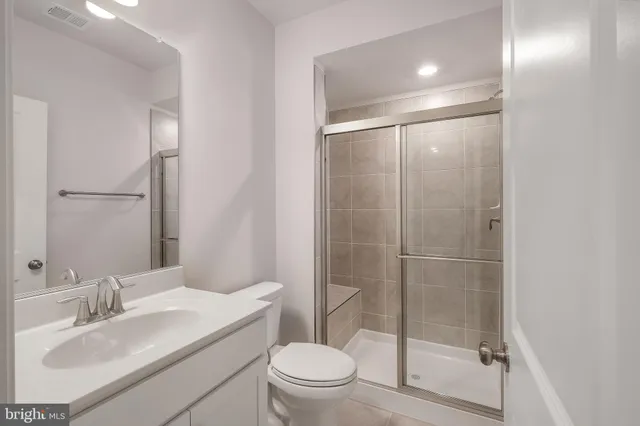 a bathroom with a shower sink vanity mirror and toilet