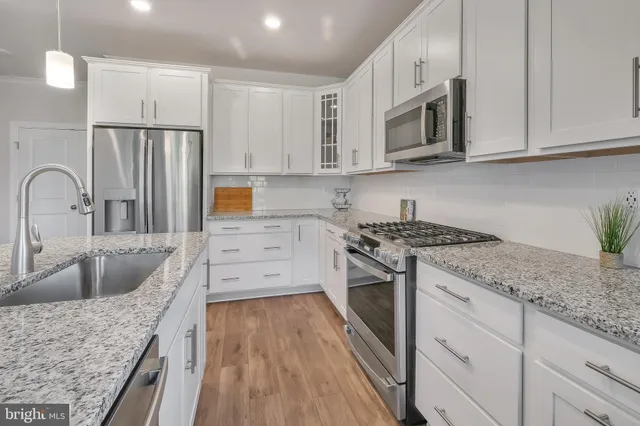 a kitchen with stainless steel appliances granite countertop a sink stove microwave and refrigerator