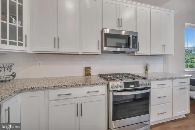 a kitchen with granite countertop white cabinets and a stove a oven with white countertops