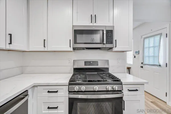 a kitchen with stainless steel appliances granite countertop grey cabinets a stove and a sink
