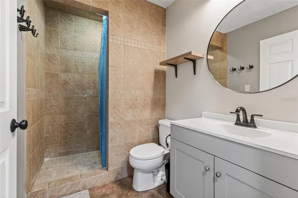 a bathroom with a toilet sink vanity granite and shower