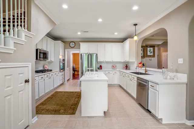 a kitchen that has a lot of white cabinets and stainless steel appliances