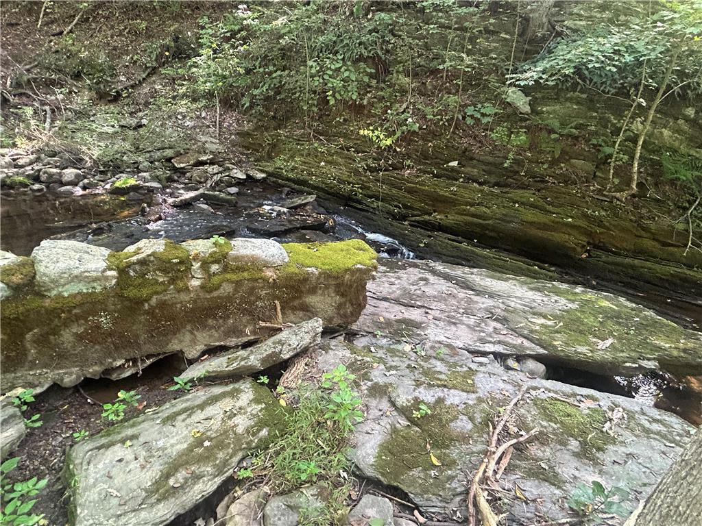 7 Allegheny Road Mount Bethel, PA 18343 - Photo 29 of 71 Natural rock formations border a gentle stream flowing through the wooded property landscape.