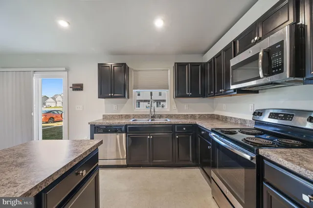 a kitchen with stainless steel appliances granite countertop a sink stove and microwave