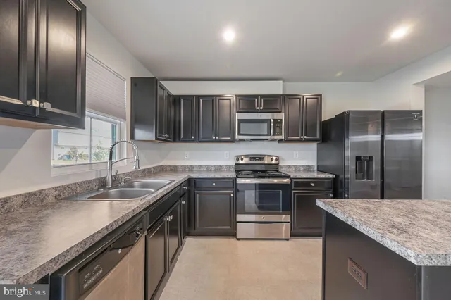 a kitchen with kitchen island granite countertop stainless steel appliances and sink