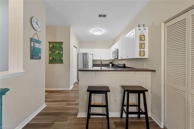 a kitchen with stainless steel appliances granite countertop a table chairs sink and cabinets