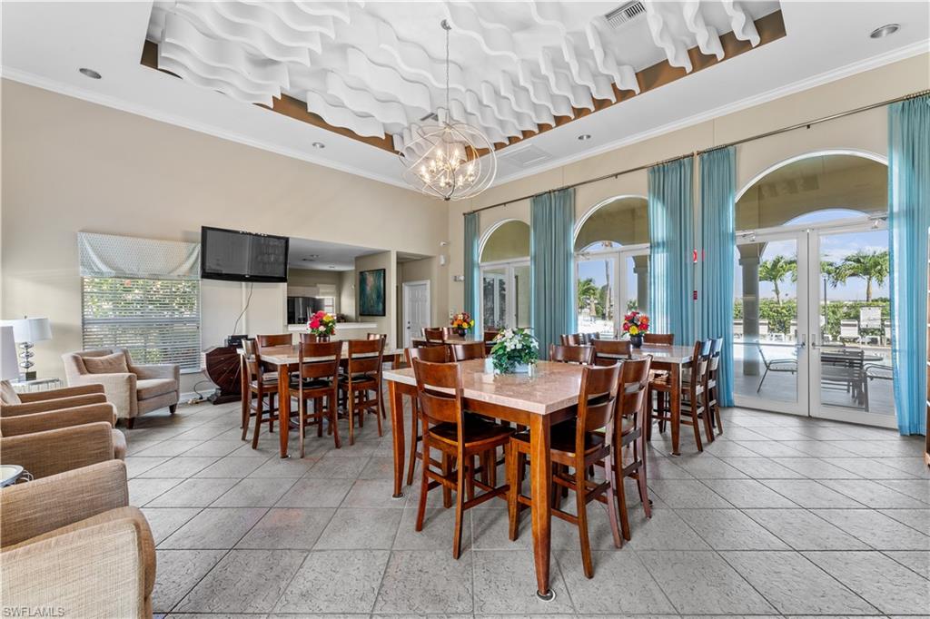 4306 Bellasol Circle, Unit 3422 Fort Myers, FL 33916 - Photo 35 of 41 Dining area featuring healthy amount of natural light, crown molding, light tile patterned flooring, a chandelier, and a high ceiling