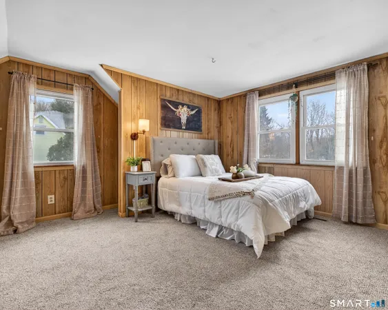 a bedroom with a bed lamp and a large window