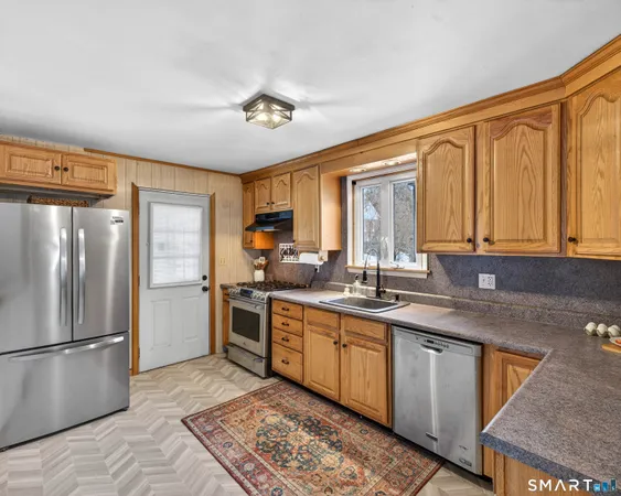 a kitchen with stainless steel appliances granite countertop a refrigerator a sink dishwasher a stove with wooden cabinets and floor