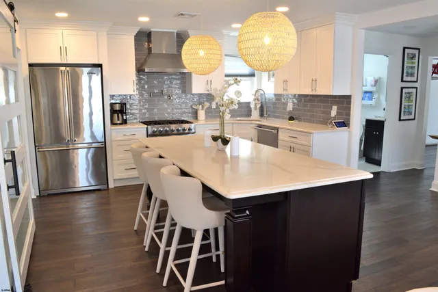 a kitchen with stainless steel appliances a dining table chairs and wooden floor
