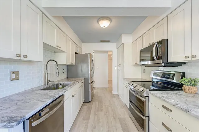 a kitchen with stainless steel appliances granite countertop a stove a sink and a refrigerator