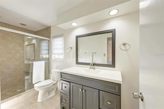 a bathroom with a toilet a sink a mirror and a shower