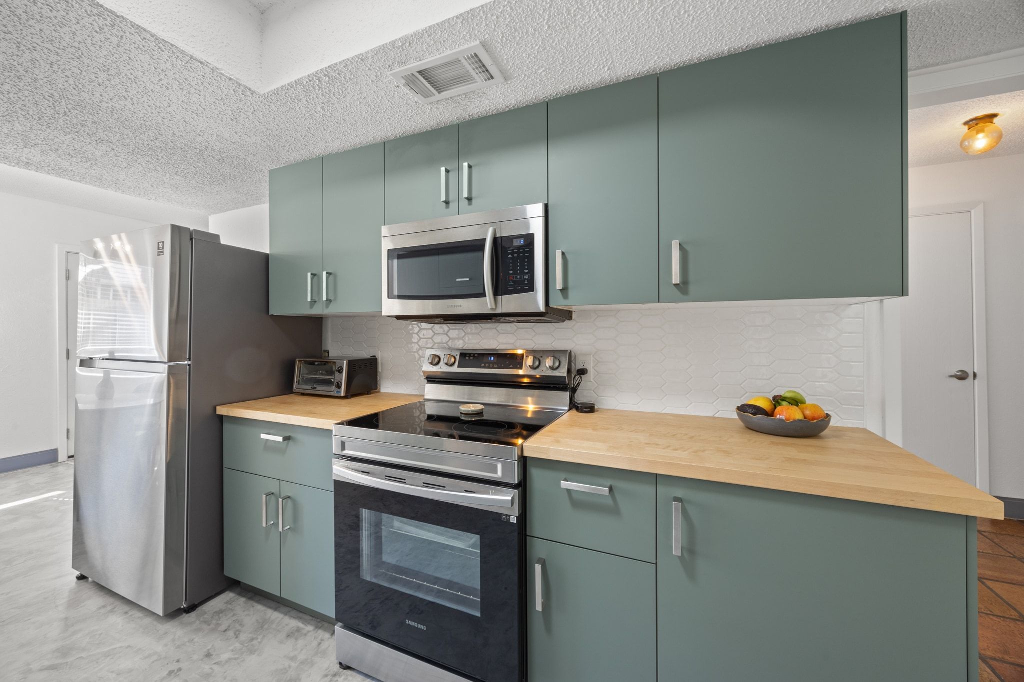 7256 Coronado Circle Austin, TX 78752 - Photo 15 of 26 Kitchen with a textured ceiling, stainless steel appliances, wooden counters, decorative backsplash, and green cabinetry