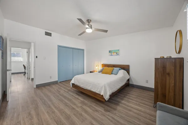 a spacious bedroom with a bed and wooden floor