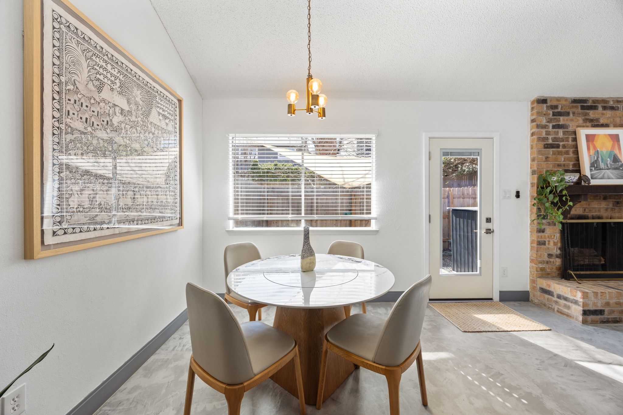 7256 Coronado Circle Austin, TX 78752 - Photo 3 of 26 Dining room featuring a fireplace, a textured ceiling, concrete floors, healthy amount of natural light, and suspended lighting