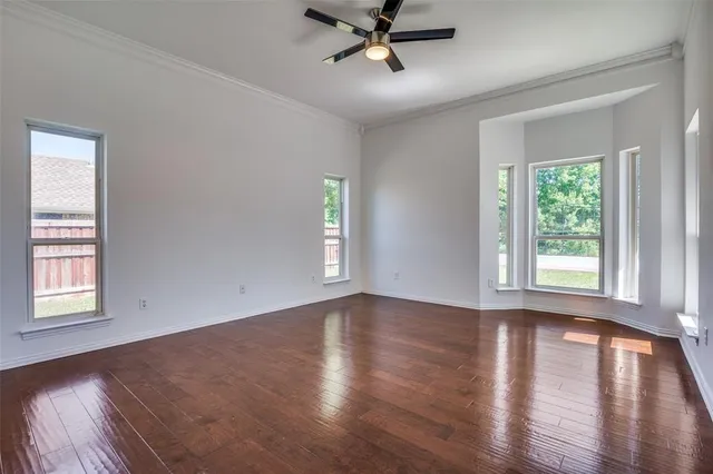 a view of empty room with wooden floor and fan